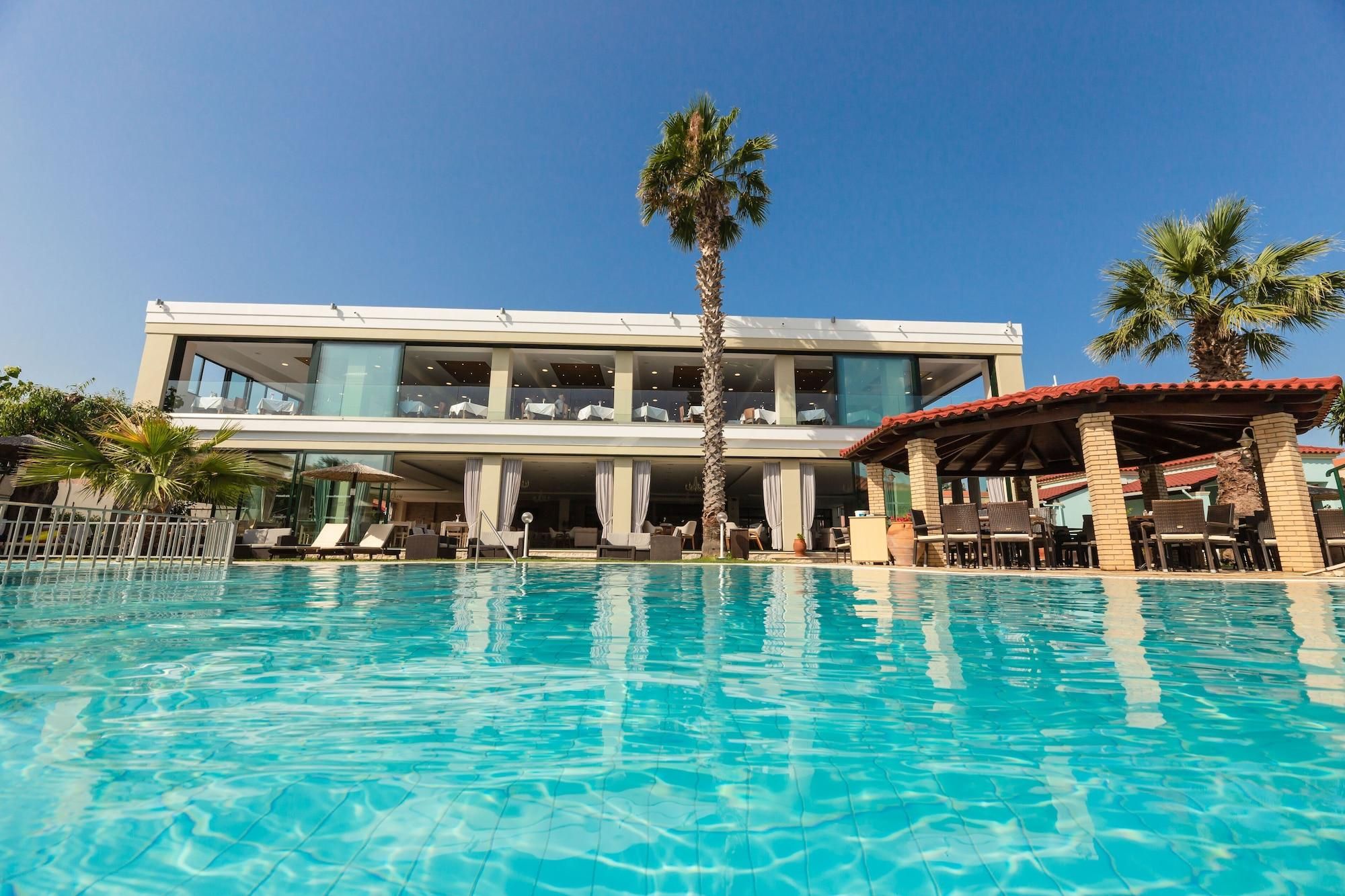 A modern hotel with a pool, outdoor seating, and palm trees.
