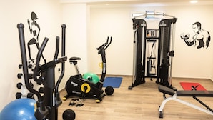 A gym with exercise equipment, a blue exercise ball, and a wall with fitness-themed artwork. - Robolla Beach (Corfu)