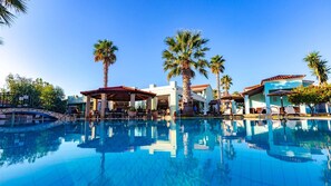A pool area with lounge chairs, palm trees, and a bridge. - Robolla Beach (Corfu)