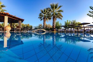 A clear blue pool with a stone bridge, palm trees, and lounge chairs. - Robolla Beach (Corfu)