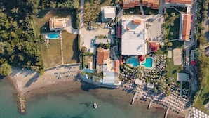 An aerial view of a resort with multiple buildings, swimming pools, and a beach area. - Robolla Beach (Corfu)