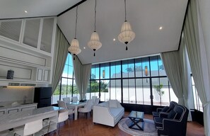 Una sala de estar moderna con comedor, ventanas amplias y cocina.