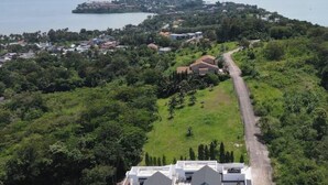 Una proprietà costiera con una strada che conduce a una casa, immersa nel verde e con vista sul mare.