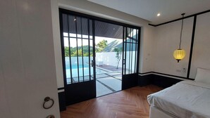 Camera da letto con un'ampia porta-finestra scorrevole che si apre su una zona piscina.