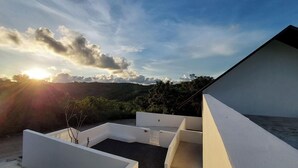 Una terrazza moderna all'aperto con vista libera sul tramonto e sulle colline circostanti.