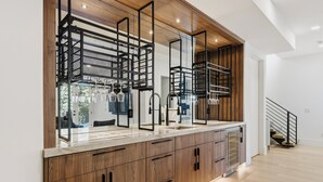 Une cuisine moderne avec des meubles en bois, un meuble à vin intégré et un évier en acier inoxydable.