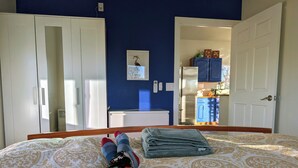 A bedroom with a bed, a wardrobe, and a view into the kitchen. - Airy 1-bedroom townhome in charming Aurora with AC (Aurora)