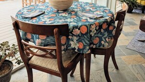 A round table with a floral tablecloth, wooden chairs, and a bowl on the table. - Airy 1-bedroom townhome in charming Aurora with AC (Aurora)