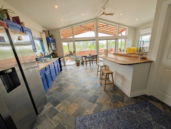 A modern kitchen with a central island, blue cabinets, and a stone floor.