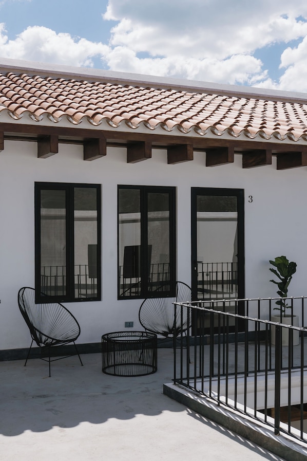 A building with a tiled roof, large windows, and a balcony with a railing.