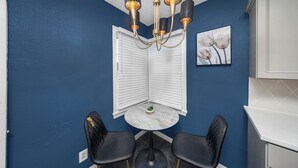 A corner room with a blue wall, a white door, a round table with two black chairs, and a chandelier. - Modern & Cozy Home Near Fort Sill (Lawton)