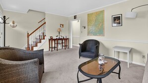 Una sala de estar con una escalera, un comedor y un mapa grande en la pared.
