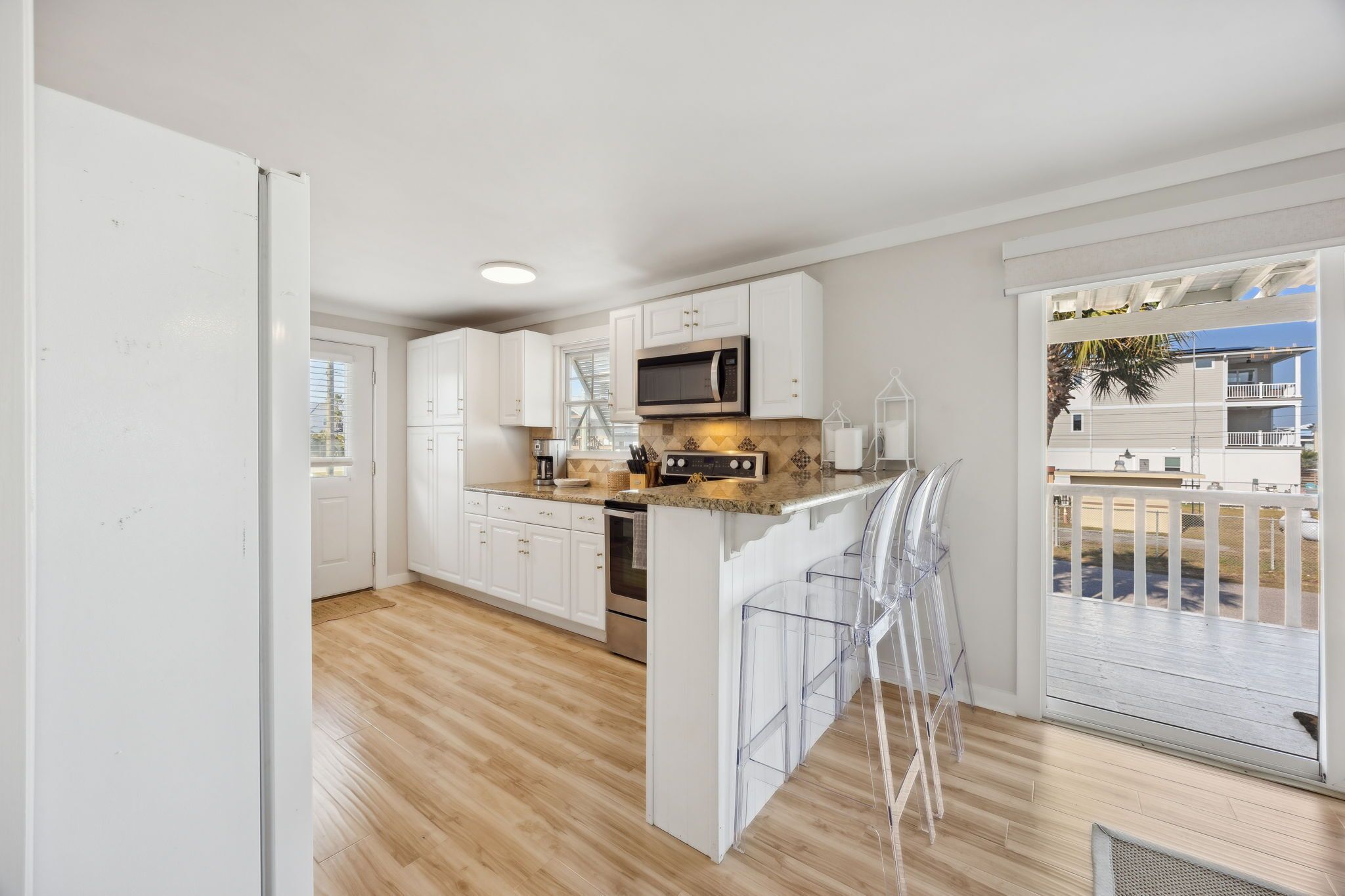 A modern kitchen with white cabinets, a microwave, and a wooden floor.