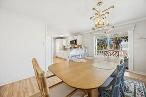 Ein Essbereich mit Holztisch, Korbstühlen und einer Chandelier.