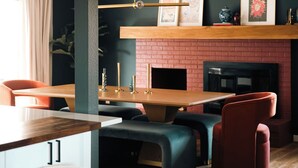 Ein moderner Essbereich mit Kamin aus Backsteinen, einem Holztisch und bequemen Sitzgelegenheiten.