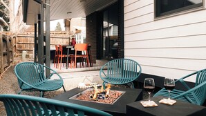 Eine Terrasse im Freien mit türkisfarbenen Stühlen, einer Feuerstelle und einem Tisch mit Weingläsern.