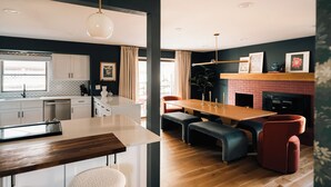 Eine moderne Küche mit Kochinsel, einem Essbereich mit Holztisch und Bänken sowie einem Kamin.