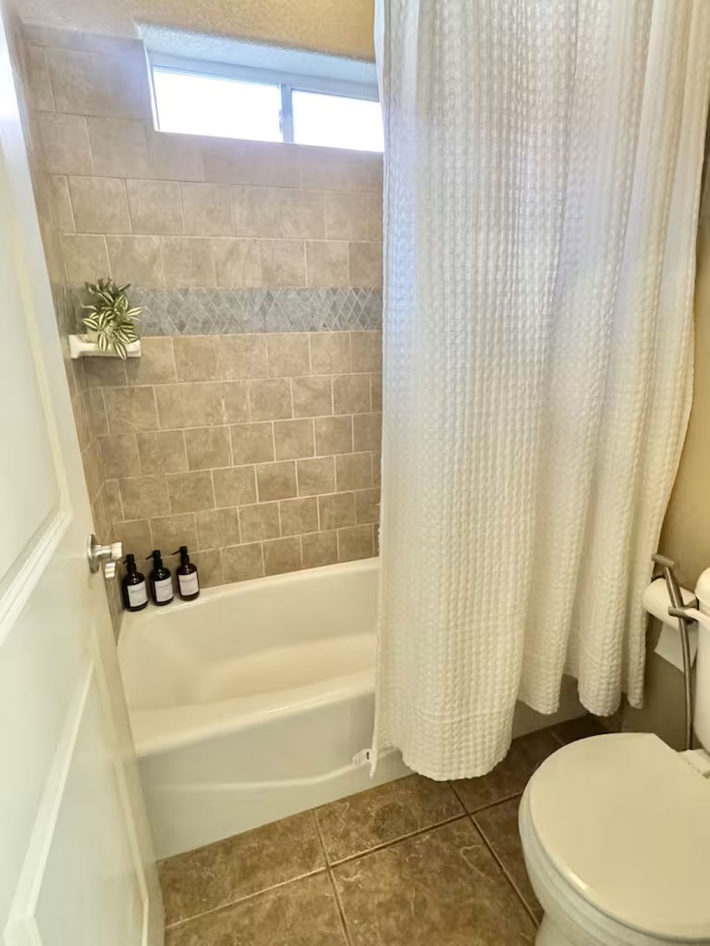 Un baño con bañera, inodoro y cortina de ducha.