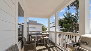 A covered porch with a grill, wicker furniture, and a table. - The Lazy Yorkie | Family Beach Getaway | Sleeps 10 | Great Rates (Inlet Beach)