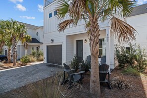 Ein zweistöckiges Haus mit Garage, überdachter Terrasse und einem Palmenbaum.