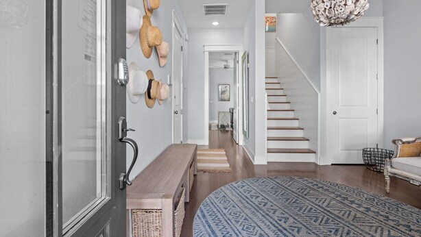 A hallway with a wooden bench, a patterned rug, and a staircase leading to another room. - The Lazy Yorkie | Family Beach Getaway | Sleeps 10 | Great Rates (Inlet Beach)