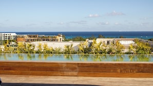 A rooftop pool with a view of the ocean and surrounding buildings. - Paravian 704 2BR Condo Playa del Carmen (Playa del Carmen)
