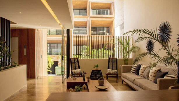 A modern living room with a sofa, chairs, a coffee table, and potted plants. - Paravian 704 2BR Condo Playa del Carmen (Playa del Carmen)