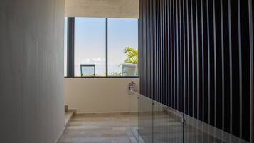 A corridor with a glass railing, a fire extinguisher, and a view of the outdoors.