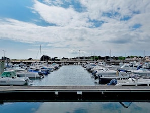 A marina with numerous boats docked along a calm waterway, surrounded by a small town with buildings and trees in the background. - Les Sternes - ETEL - Vacation Home (ETEL)
