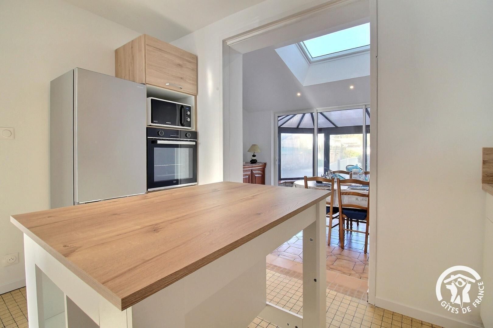 Una cocina moderna con encimera de madera, electrodomésticos integrados y un tragaluz.