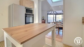 A modern kitchen with a wooden countertop, built-in appliances, and a skylight. - Les Sternes - ETEL - Gîte (ETEL)