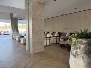 A modern lobby with a seating area, large planters, and a view of the parking area. - Near the beach in the marina with beautiful views (Mazatlán)