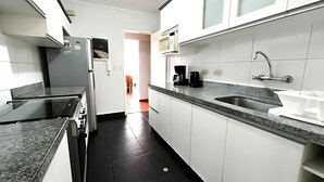 Une cuisine moderne avec des meubles blancs, un plan de travail en granit, un évier et une machine à café.