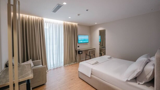 Una habitació d'hotel moderna amb un llit gran, una taula de treball i una televisió.