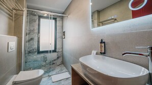 Ein modernes Badezimmer mit einem großzügigen, freistehenden Waschbecken, einer Glasdusche und einer Toilette.