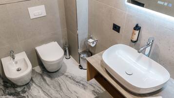 A modern bathroom with a bidet, toilet, and sink.