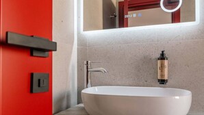 Ein modernes Badezimmer mit einem weißen Waschtischbecken, einem Chromarmaturen und einem Spiegel über dem Becken.