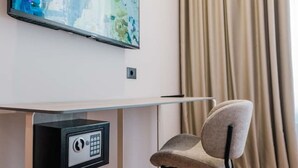 Ett modernt rum med ett skrivbord, en stol, en tavla och ett fönster med gardiner.