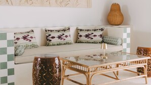 Un soggiorno moderno con un divano, cuscini decorati, un tavolino in vetro e un vaso ornamentale.