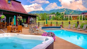 A pool area with a hot tub, lounge chairs, and a view of mountains. - Brand new, 5BR home with private shuttle and concierge (Steamboat Springs)