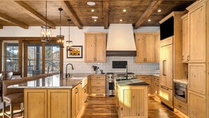 A spacious kitchen with wooden cabinets, a large island, and a built-in oven. - Brand new, 5BR home with private shuttle and concierge (Steamboat Springs)