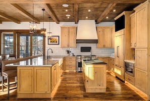 A spacious kitchen with wooden cabinets, a large island, and a built-in oven. - Brand new, 5BR home with private shuttle and concierge (Steamboat Springs)