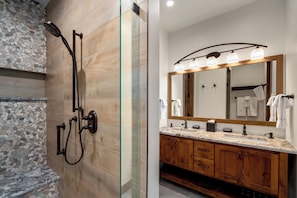 A modern bathroom with a glass-enclosed shower, wooden vanity, and a large mirror with lights. - Beautiful 3BR retreat in Steamboat Springs with mountain views. (Steamboat Springs)