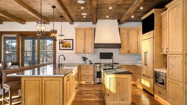 A spacious kitchen with wooden cabinets, a large island, and a stone backsplash. - Brand New! 8BR home, private shuttle and concierge (Steamboat Springs)