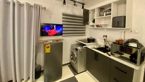 A compact kitchen with a washing machine, a TV mounted above the counter, and a ceiling light fixture. - Serene 1-bedroom studio with AC in vibrant Accra (Accra)