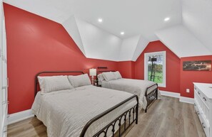 Ein Schlafzimmer mit zwei Betten, einem Fenster und einer roten Wand.