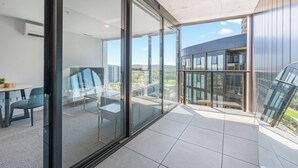 A modern apartment with a balcony, large windows, and a view of the cityscape. - Modern and Cozy 1-Bedroom Apartment in Phillip (Phillip)
