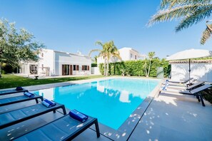 A swimming pool with lounge chairs, a white building, and a well-maintained garden. - Villa Marbella, a short walk from the beach (Marina di Ragusa)
