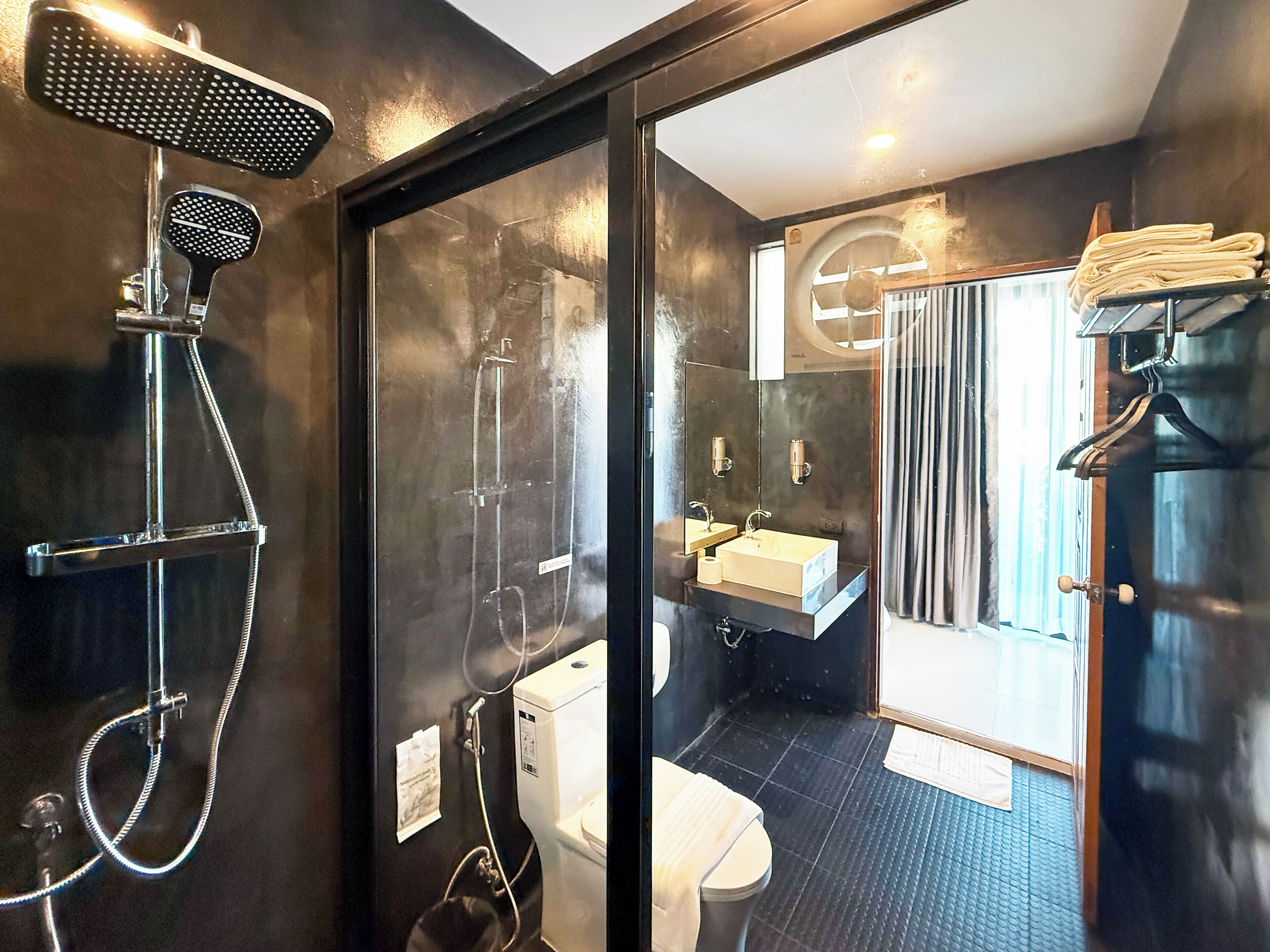 Un baño moderno con mampara de vidrio, ducha, inodoro, lavabo y espejo.