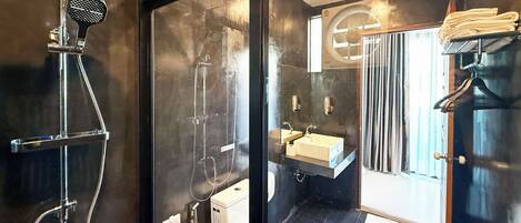 Un baño moderno con mampara de vidrio, ducha, inodoro, lavabo y espejo.